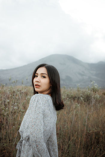 Beautiful young woman standing on land against sky