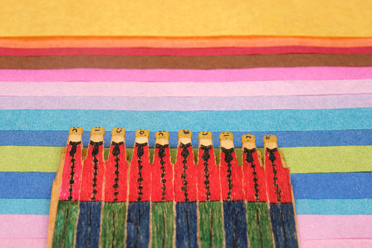 Matchsticks with faces painted on the heads on multicolored paper
