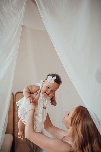 Mother and baby girl on bed at home