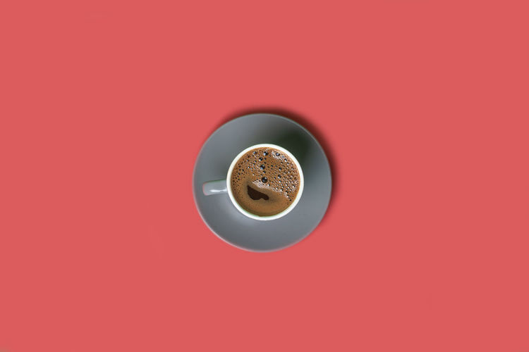 Directly above shot of coffee cup against red background