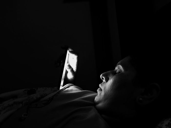 Young woman using mobile phone in darkroom