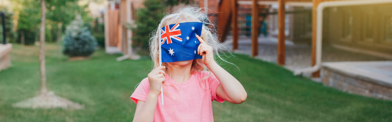 Cute girl holding australian flag at lawn