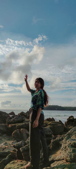 Portrait of woman standing on rocks against sky