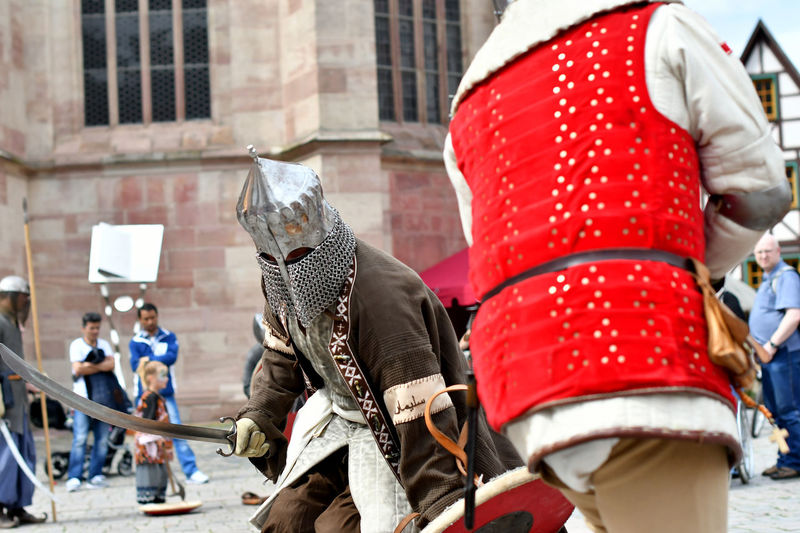 People looking at men in period costume fighting during knight tournament