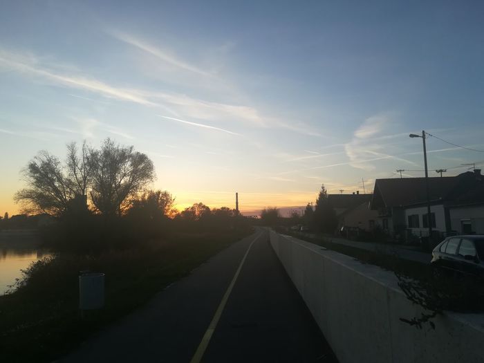 Road in city against sky during sunset