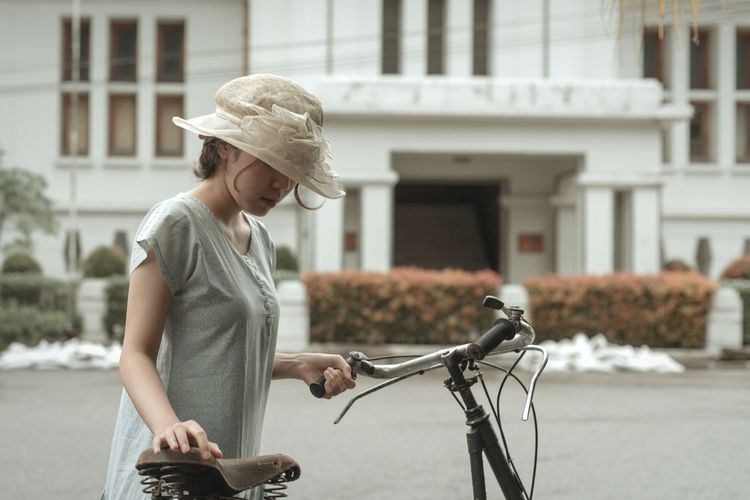 Woman wearing hat with bicycle on field