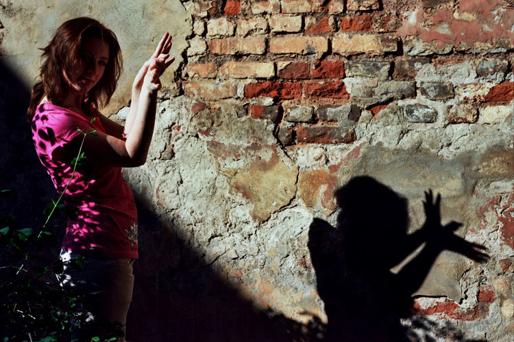 Woman playing against brick wall