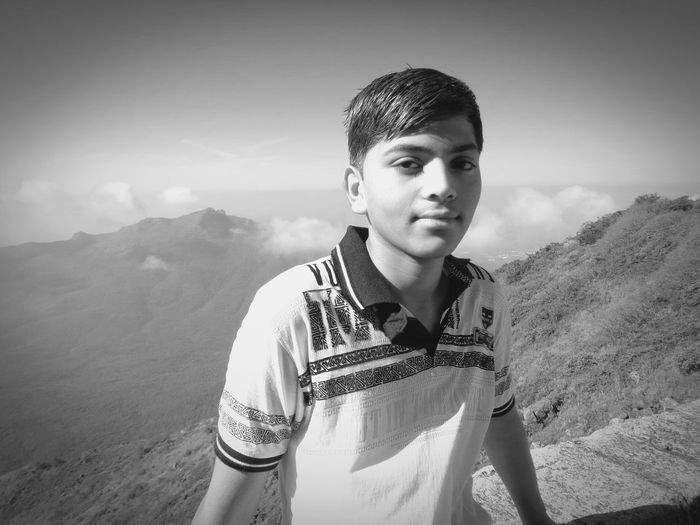 Portrait of boy standing on mountain against sky