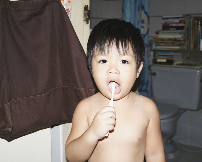 Portrait of shirtless boy holding toothbrush at home