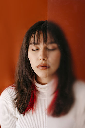 Young woman with eyes closed behind plastic sheet