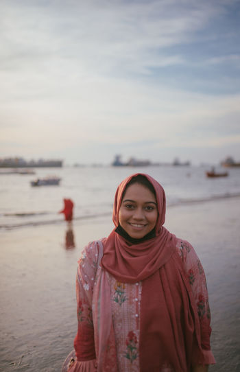 Portrait of a smiling young woman standing on beach
