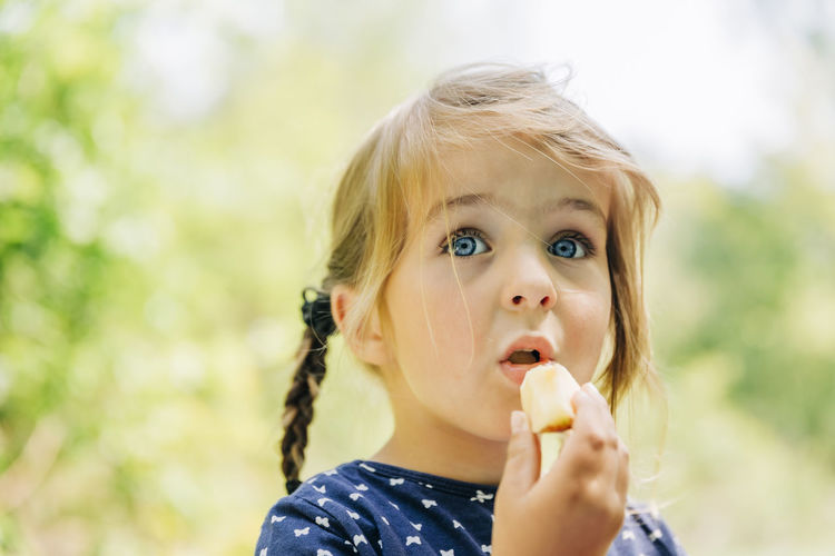 Close-up of cute girl with blue eyes eating food