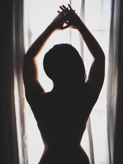 Close-up of silhouette woman standing against window