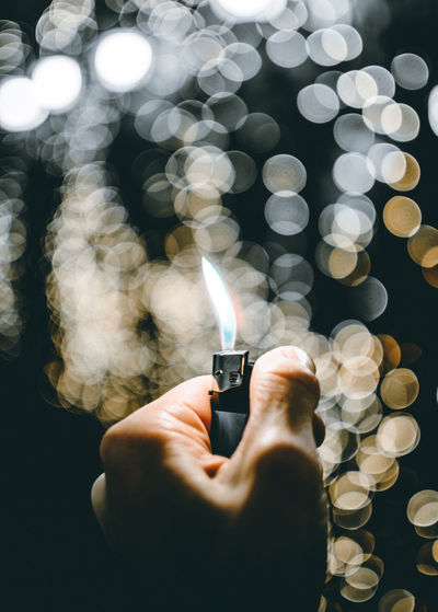 Close-up of hand holding cigarette lighter with flame