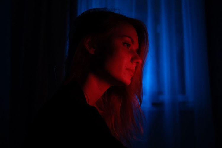 Portrait of beautiful young woman. girl in red and blue light at night