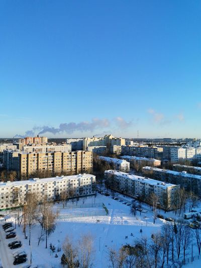 Snow covered buildings against blue sky