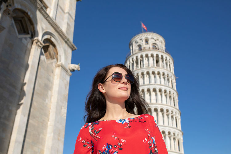 Woman wearing sunglasses while standing against leaning tower of pisa