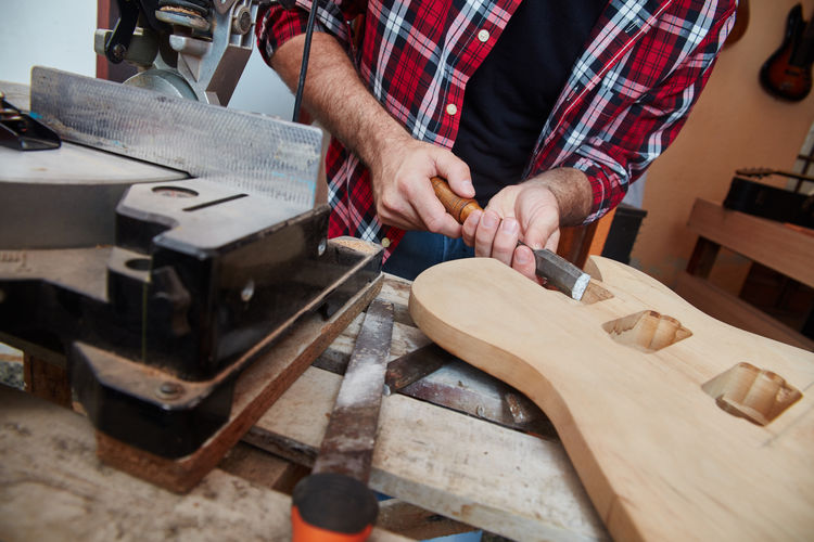 Midsection of man working on guitar over table