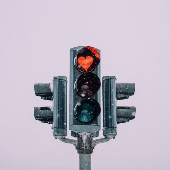 Close-up of road signal against clear sky during winter