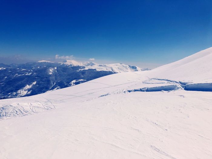 Scenic view of snowcapped mountains against blue sky