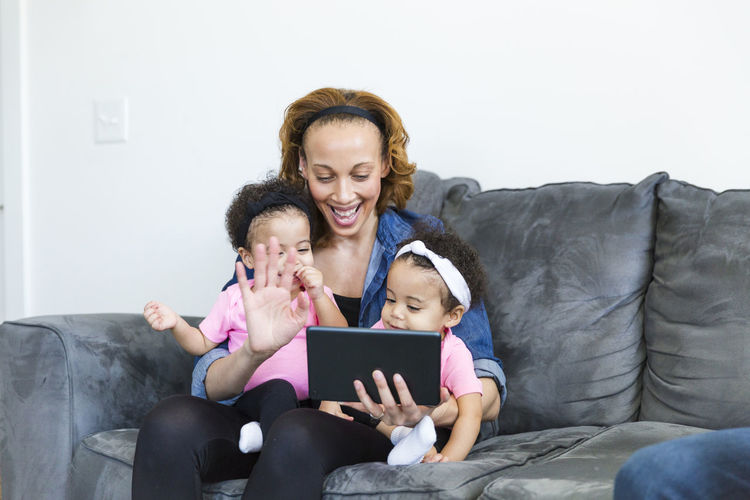 Happy mother and daughters video conferencing on tablet computer