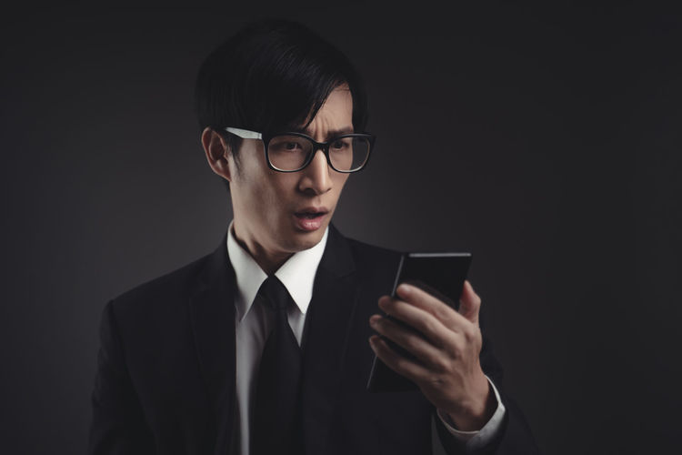 Young man using smart phone against black background