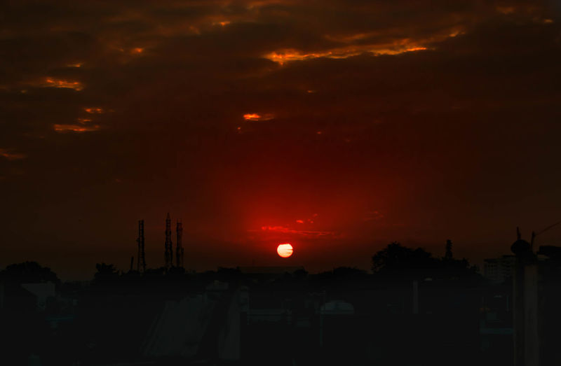 Silhouette buildings against dramatic sky during sunset