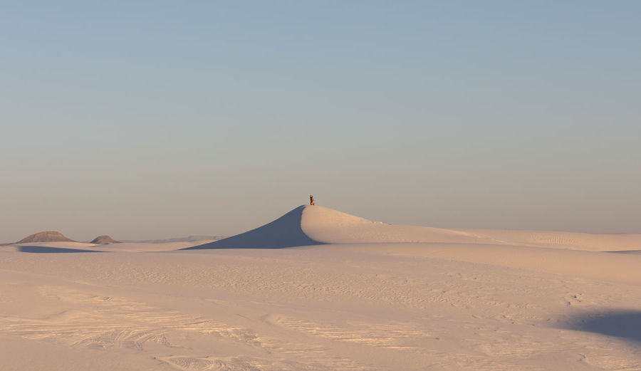 A couple on the dunes of white sands national park at sunset