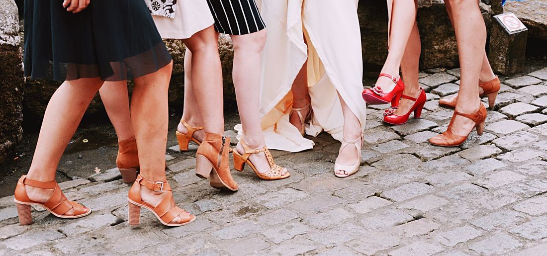 Low section of women in high heels standing on footpath
