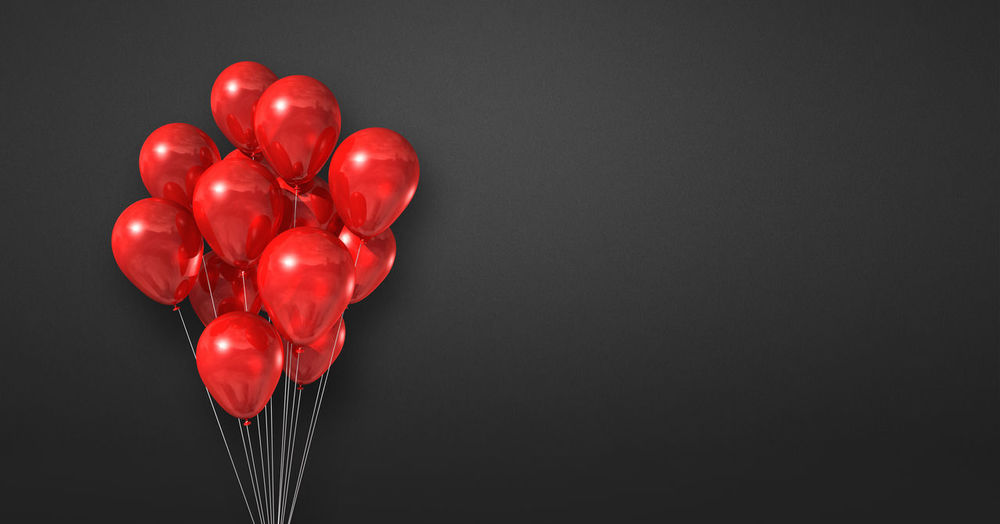 Directly above shot of red heart shaped balloons against black background