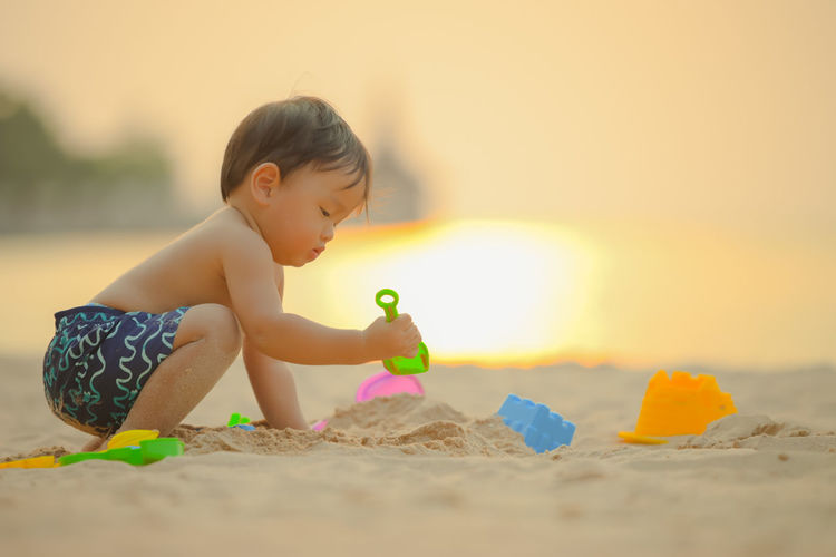 Cute boy playing with toy on beach