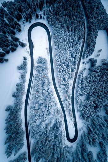 Aerial view of winding road amidst trees during winter