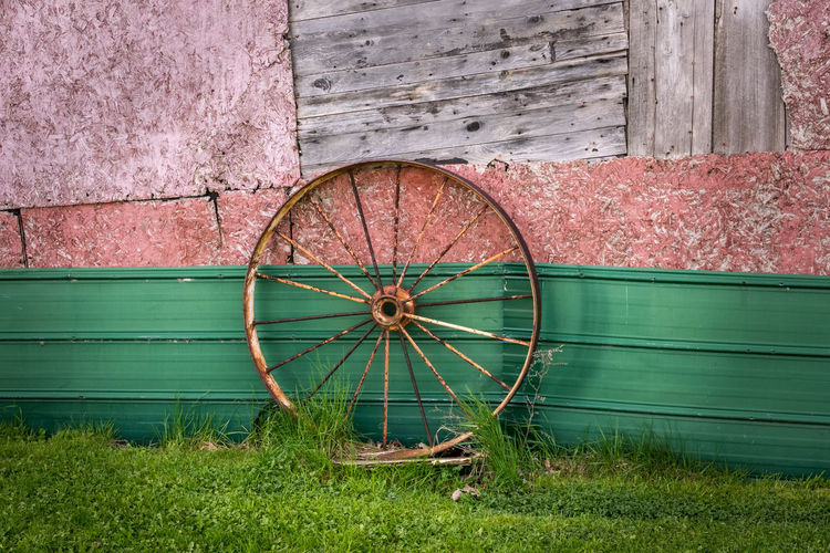 Abandoned wheel on field against wall