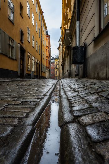 Wet street in gamla stan area of stockholm amidst buildings in city during rainy season