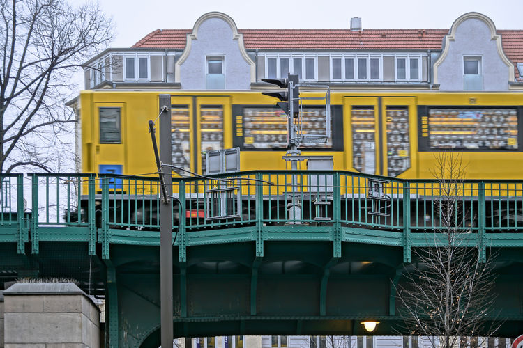Low angle view of yellow train on railway bridge in city