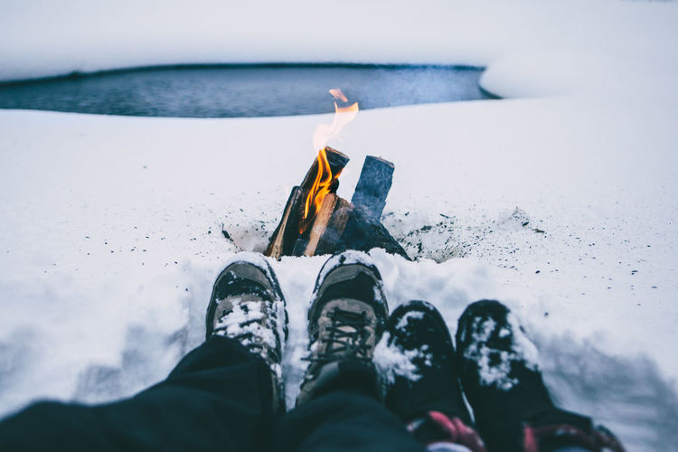 Low section of couple sitting on snow covered field