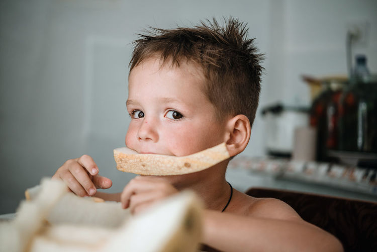 Portrait of cute boy eating bread at home