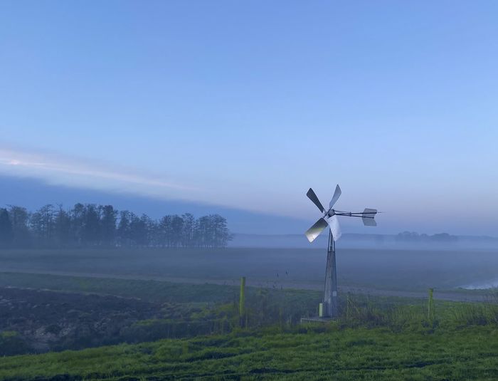 Scenic view of metal windmill against foggy sky