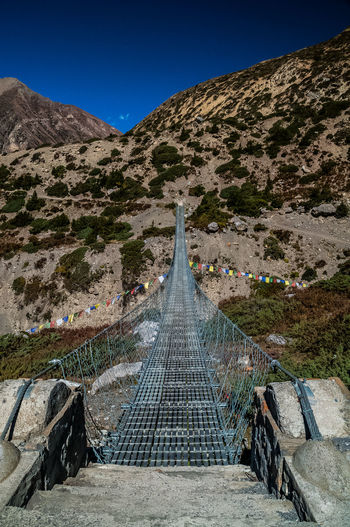 Tibetan bridge over mountain against blue sky