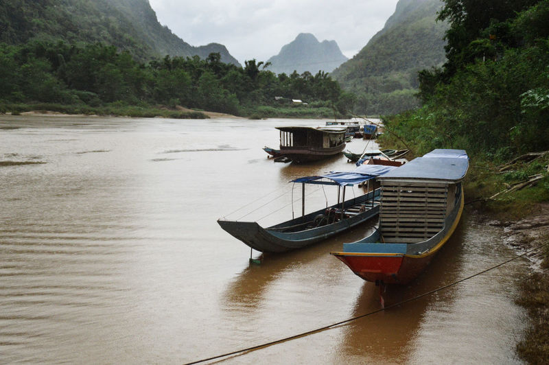 Boat moored on river against mountains
