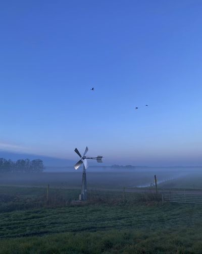 Scenic view of small metal windmill on a green pasture