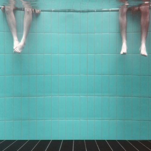 Underwater view of legs dangling in swimming pool