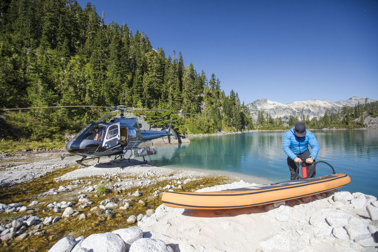 Adventurous man pumps up inflatable sup next to a remote lake.