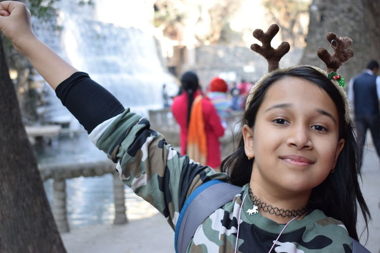 Portrait of smiling girl wearing horn headband at park