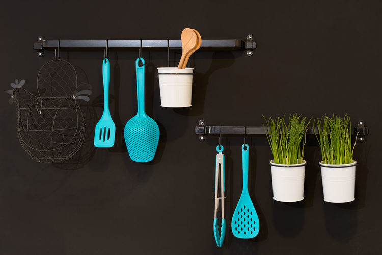 Close-up of kitchen utensils hanging from rack against wall in kitchen