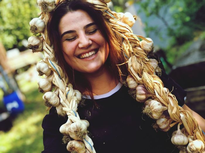 Close-up of smiling woman with garlic outdoors