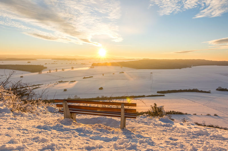 Scenic view of snow covered field against sky during sunset