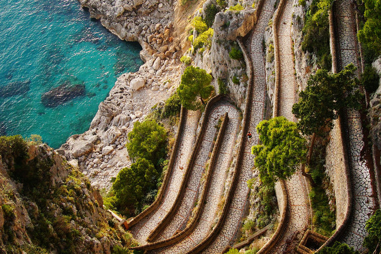 High angle view of narrow curved road against cropped sea