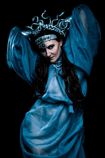 Portrait of young woman wearing mask against black background