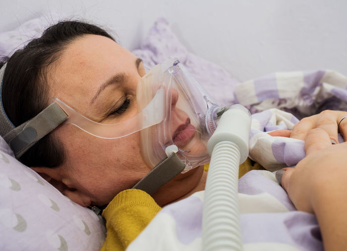 High angle view of woman with oxygen mask lying on bed